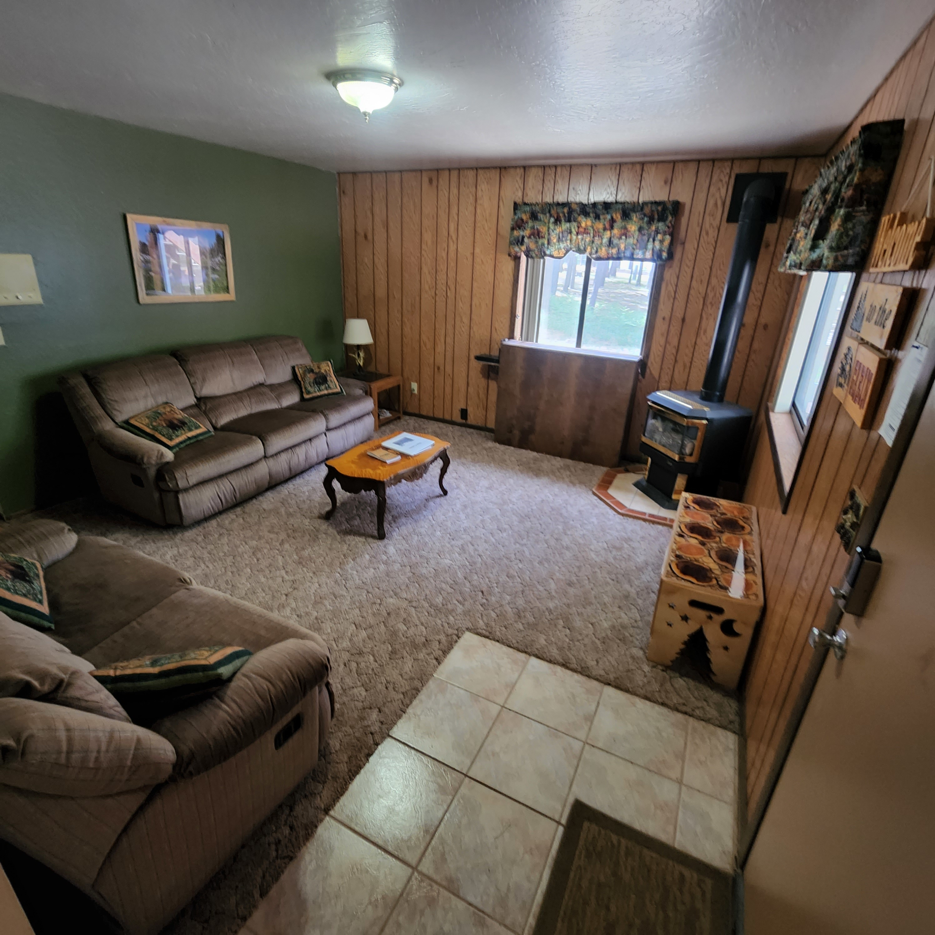 Family Room - The family room area features 2 comfortable recliner couches and a gas stove. It also has a large screen smart TV shown here in the down position, as well as a DVD player. When not in use the TV drops into a cabinet so you can enjoy the full view from the windows.